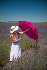 Woman with pink umbrella in a lavender field