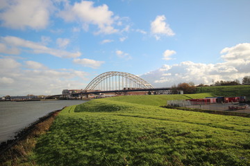 Bridge over river the Noord in the Netherlands with blue sky and big white clouds
