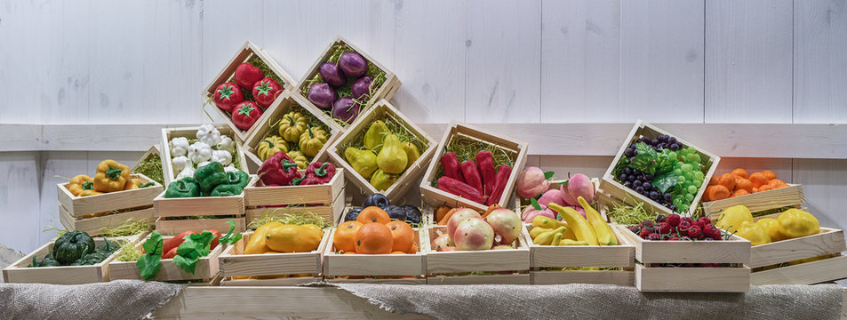 Decorative vegetables, fruits and berries lie in square boxes on the counter.