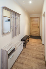 Corridor in the flat. Wooden hanger on the wall.