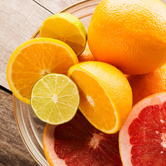 Citrus fruits - oranges, limes, grapefruits. On wooden background. square