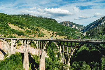 Beautiful Arch Bridge over canyon river, mountains landscape on the background