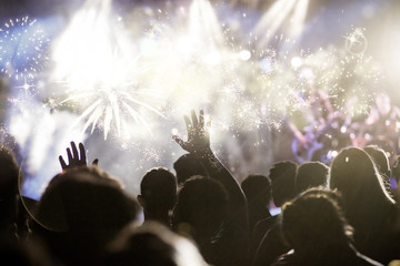 crowd with raised hands watching fireworks - New Year concept