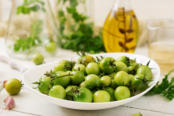 Green tomatoes in a white bowl. Preparation for pickling.