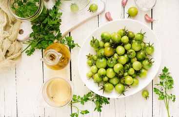 Green tomatoes in a white bowl. Preparation for pickling. Flat lay. Top view