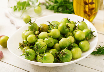 Green tomatoes in a white bowl. Preparation for pickling.