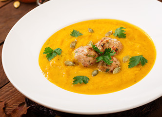 Delicious cream of pumpkin soup with meatballs made of turkey minced meat in a bowl on a wooden table. View from above. Thanksgiving Day.