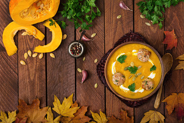 Delicious cream of pumpkin soup with meatballs made of turkey minced meat in a bowl on a wooden...