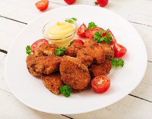 Chicken nuggets and sauce in plate on a white wooden background