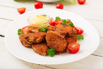 Chicken nuggets and sauce in plate on a white wooden background