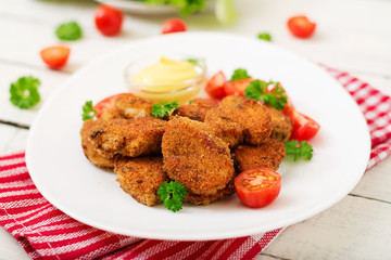 Chicken nuggets and sauce in plate on a white wooden background