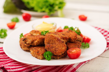 Chicken nuggets and sauce in plate on a white wooden background