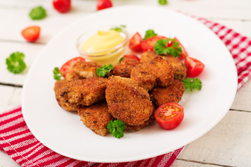 Chicken nuggets and sauce in plate on a white wooden background