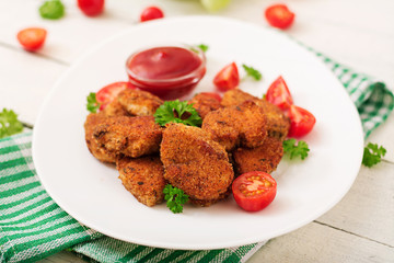 Chicken nuggets and sauce in plate on a white wooden background