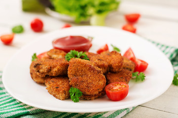 Chicken nuggets and sauce in plate on a white wooden background