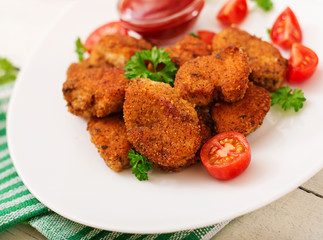Chicken nuggets and sauce in plate on a white wooden background