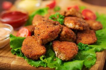 Chicken nuggets and sauce on a wooden background.