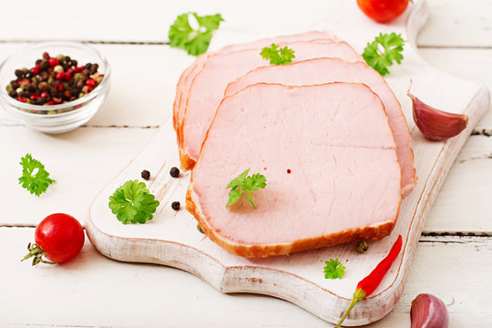 Slices of ham on white wooden background. Flat lay. Top view