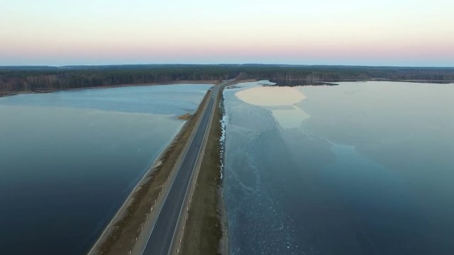 4K. Flight over road in the frozen water in winter on sunset, aerial view.