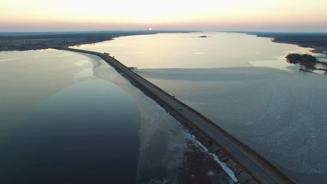4K. Aerial view of road in the frozen water with moving cars on sunset, winter top view.