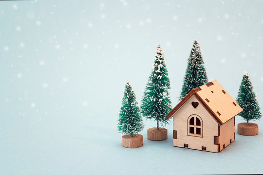 Christmas and New Year miniature  house with fir trees on blue background. Copy space for text. Winter card.