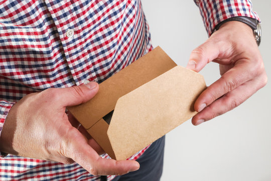 Man opening brown paper envelope