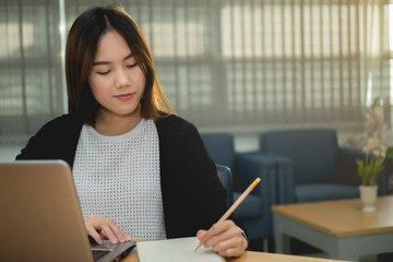 Beautiful asian woman working at the office  in the evening,Thailand worker writing book in the company