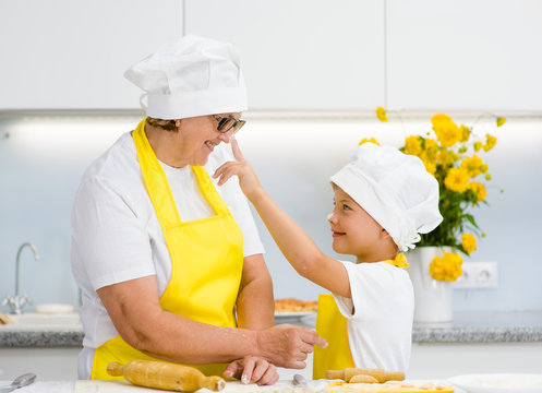 boy trying to smear nose with flour his grandmother in kitchen