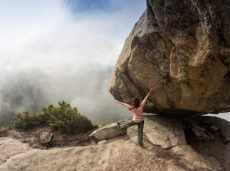 Climber is bouldering in nature. Girl climbs on a big stone. Woman doing sports outdoors. Athlete is engaged in activity outdoors.