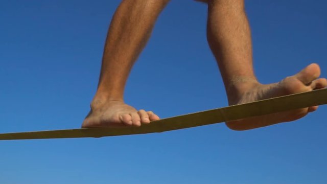 Legs of Man Walking on The Rope at the Extreme sports festival. Slackline walk