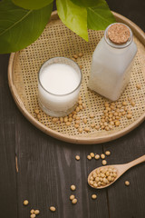 Bottle of soy milk and soybean on wooden table
