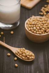 Glass with soy milk and soy bean on wooden background