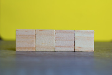 Four Empty Wood Cubes against yellow background