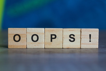 OOPS word on wood cubes on table against blue background