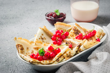 Delicious breakfast coconut flour crepes with berries jam and milk on concrete background. Selective focus, copy space. 