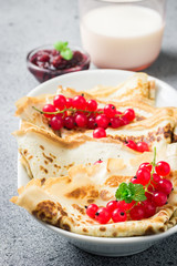 Coconut flour healthy crepes with berries jam and milk on concrete background. Selective focus, copy space. 