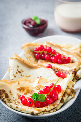 Vegan buckwheat crepes with berries jam and milk on concrete background. Selective focus, copy space. 