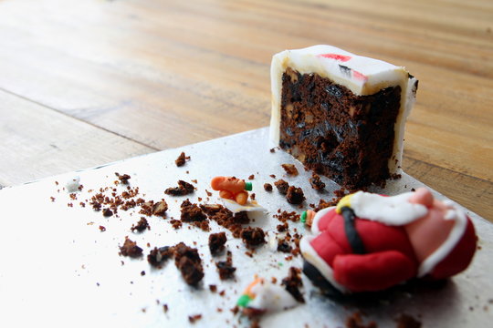 The Very Last Piece Of A Home Made Christmas Cake,with A Collapsed Sugarcraft Father Christmas, Or Santa Claus, Made From Icing Or Fondant. Copy Space For Text