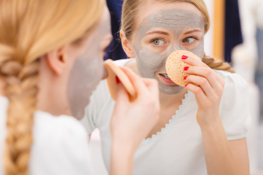 Woman Removing Mud Facial Mask With Sponge