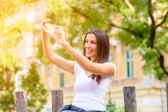 A woman in a Park taking a Selfie with her Smartphone