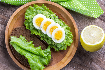 Sandwich with bread, mashed avocado, sliced eggs, green salad, tasty breakfast, healthy food