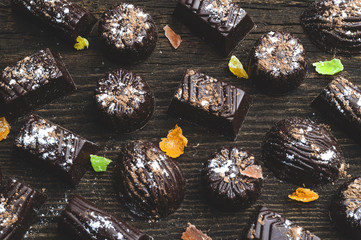 chocolate candies, candied fruits on a wooden background