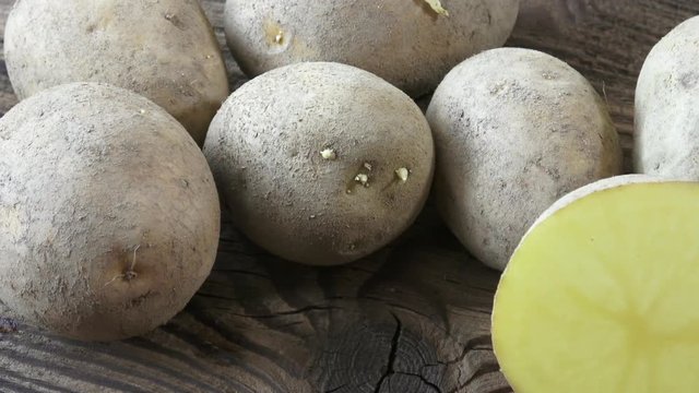Potatoes on wooden background. Unpeeled dirty raw organic potatoes
