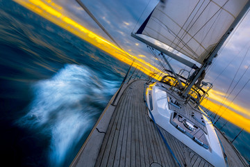 Blue water cruiser sailboat sailing through the open ocean before sunset