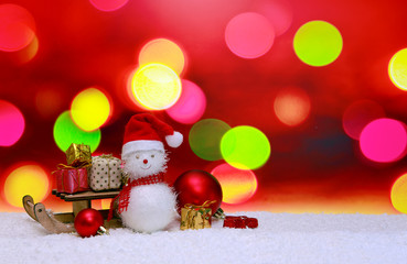 Snowman with Christmas gifts on the sledge isolated on abstract background.
