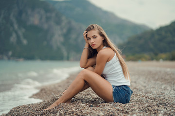 Fototapeta na wymiar beautiful girl in a white tank top on the seashore