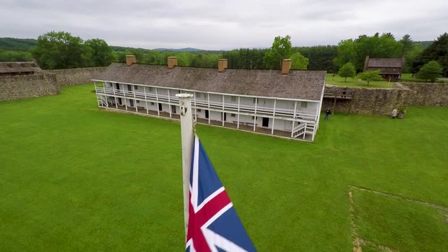 Aerial of the Calvert Arms/King&rsquo;s Colors flag waving in the breeze with the barracks in the distance at Fort Frederick in Maryland.