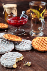 cookies with white chocolate frosting and raspberry jam in a little vase on the table for tea