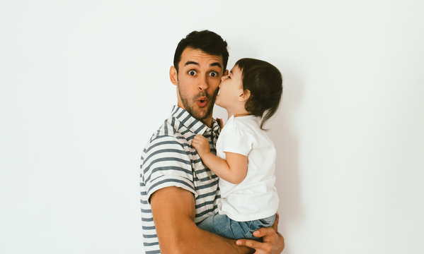 Cute toddler girl daughter kiss her surprised handsome father on cheek. Young dad embrace his child. Handsome father with little girl. Happy father and daughter. Lifestyle family.
