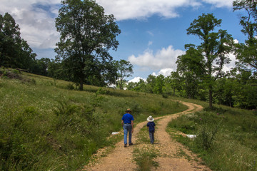 Obraz premium Man and boy walking up a dirt road.